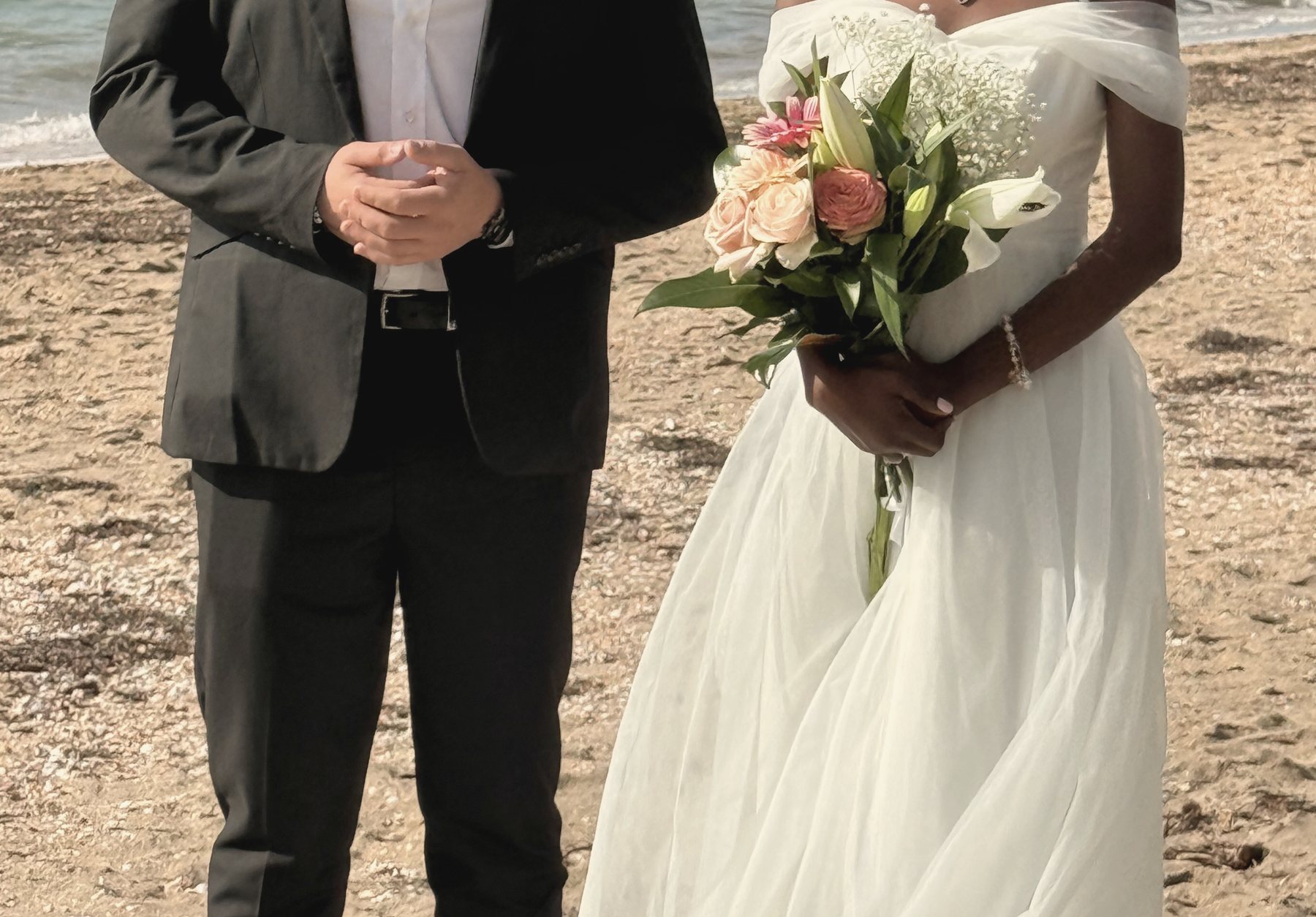 A bride’s bouquet of peach roses and lilies on the beach