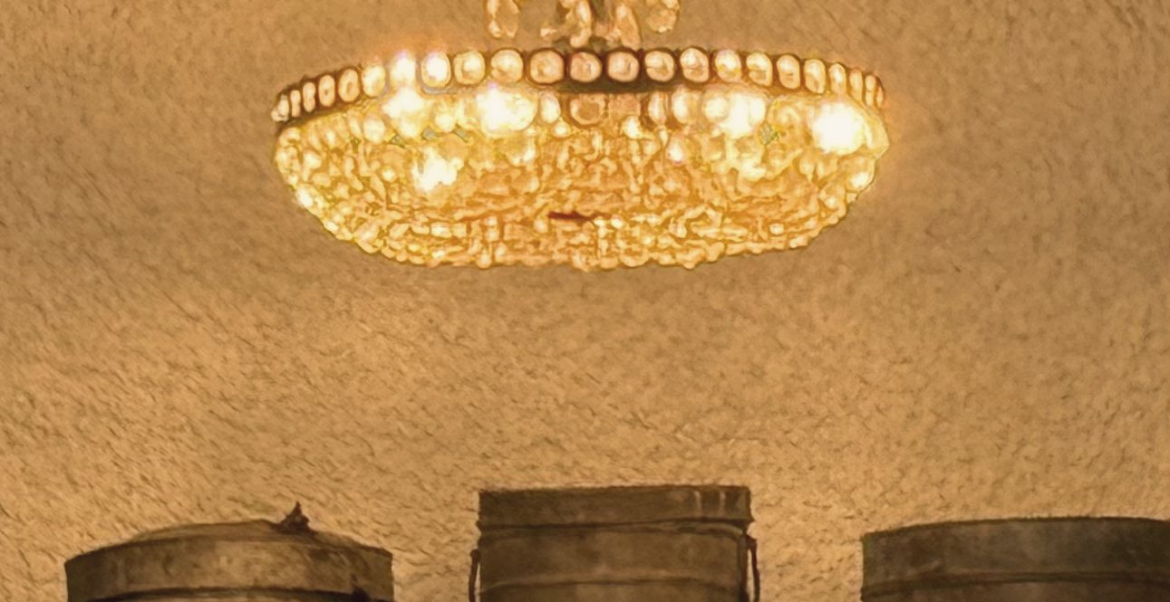 A crystal chandelier glowing in a warm arched venue