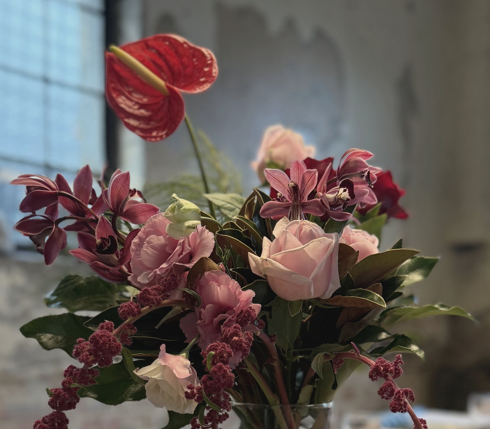 Pink roses, orchids and a red anthurium