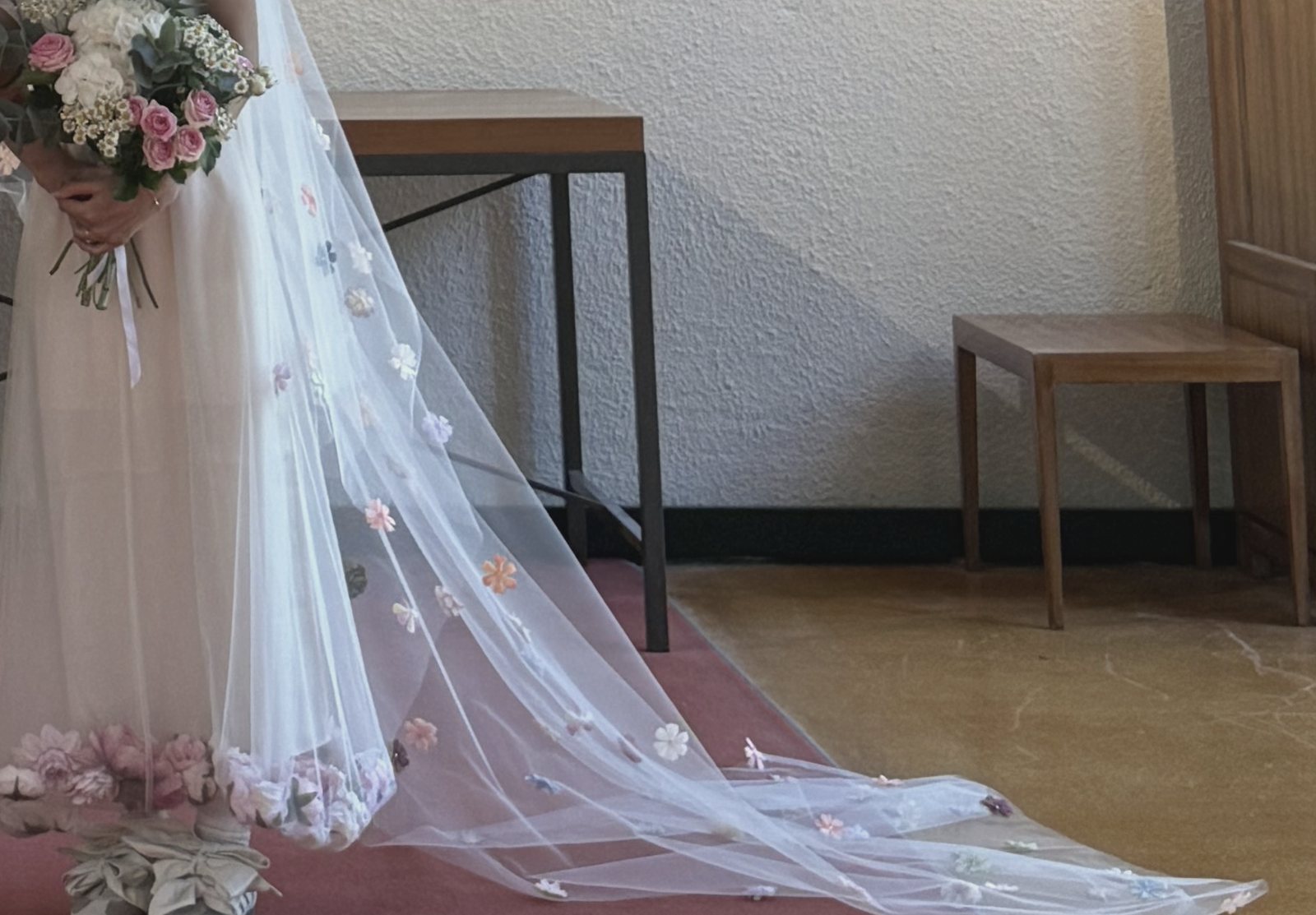 A flower-dotted veil trailing across a red carpet