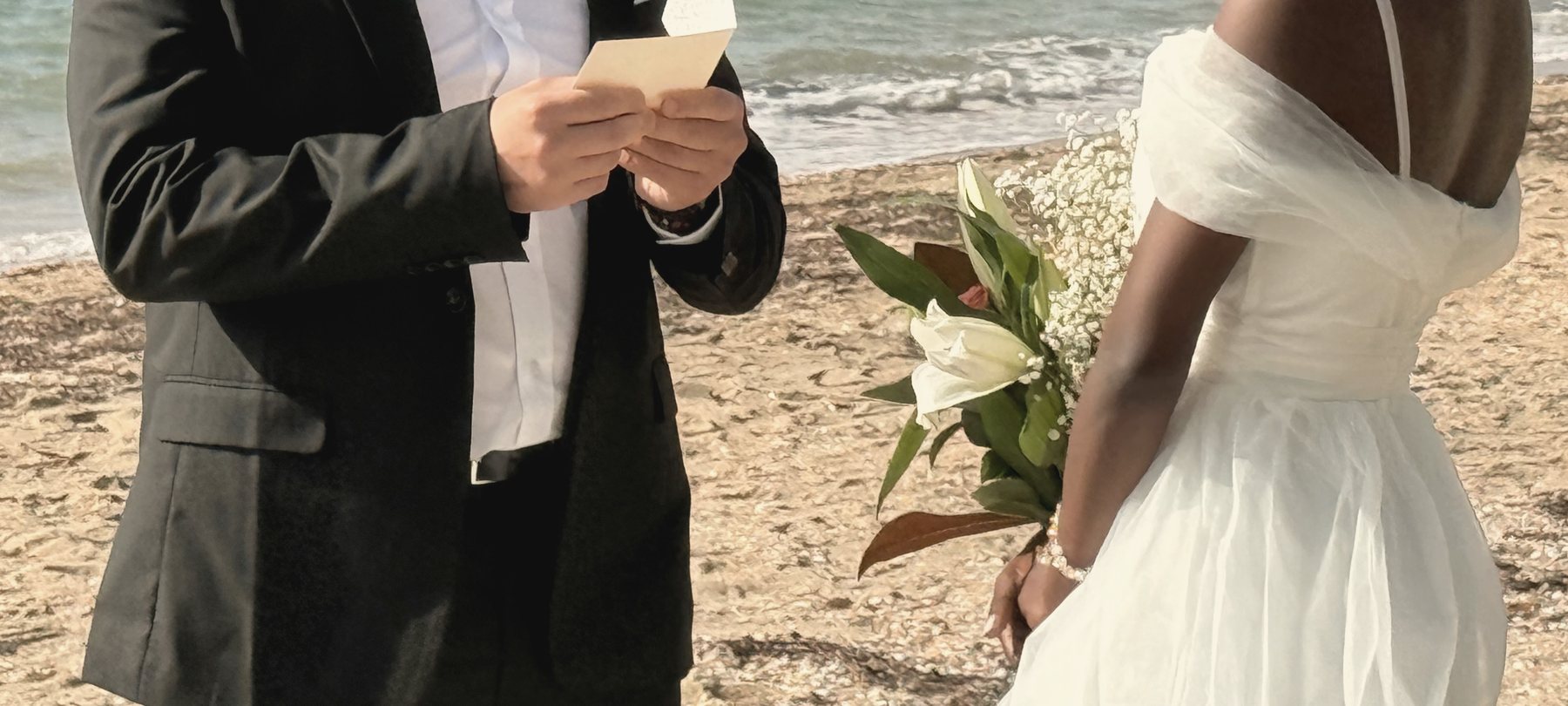 Reading vows from a handwritten card on the beach